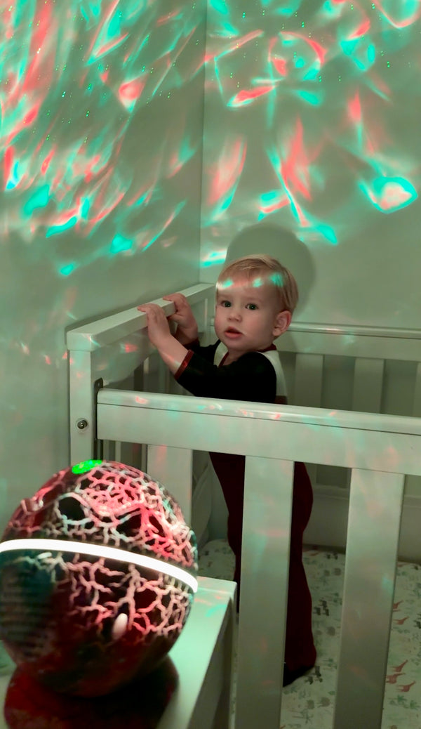 Toddler in cot with soft colours swirling of the nightlight