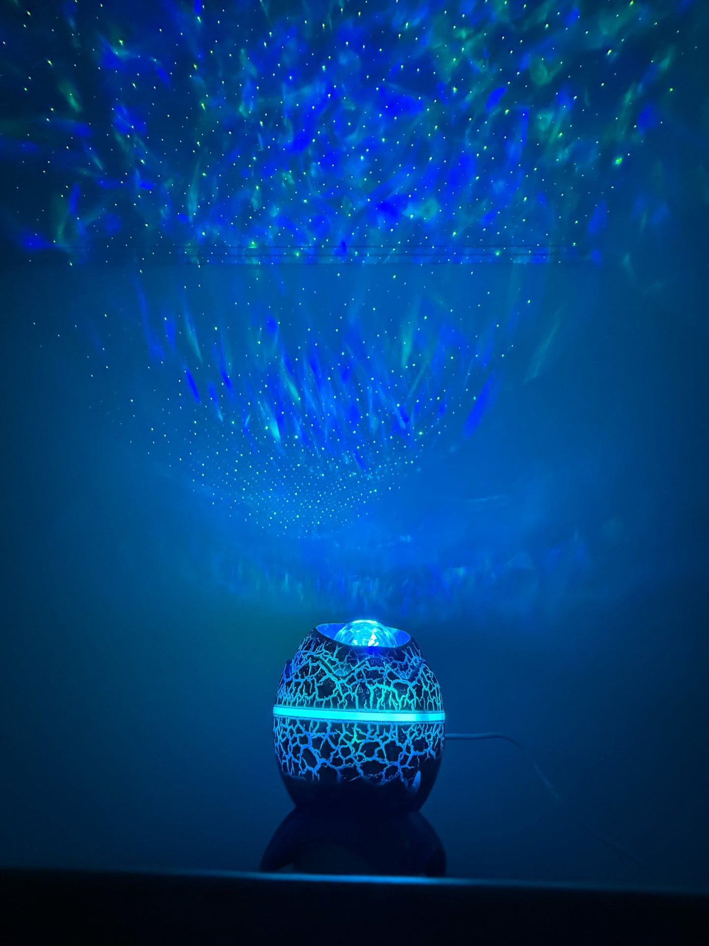 Blue light projector creating star-like patterns on a dark background
