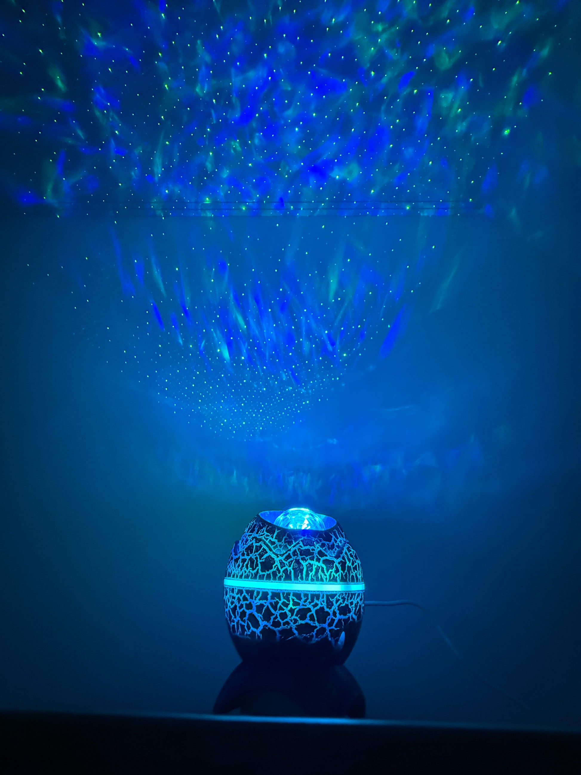 Blue light projector creating star-like patterns on a dark background